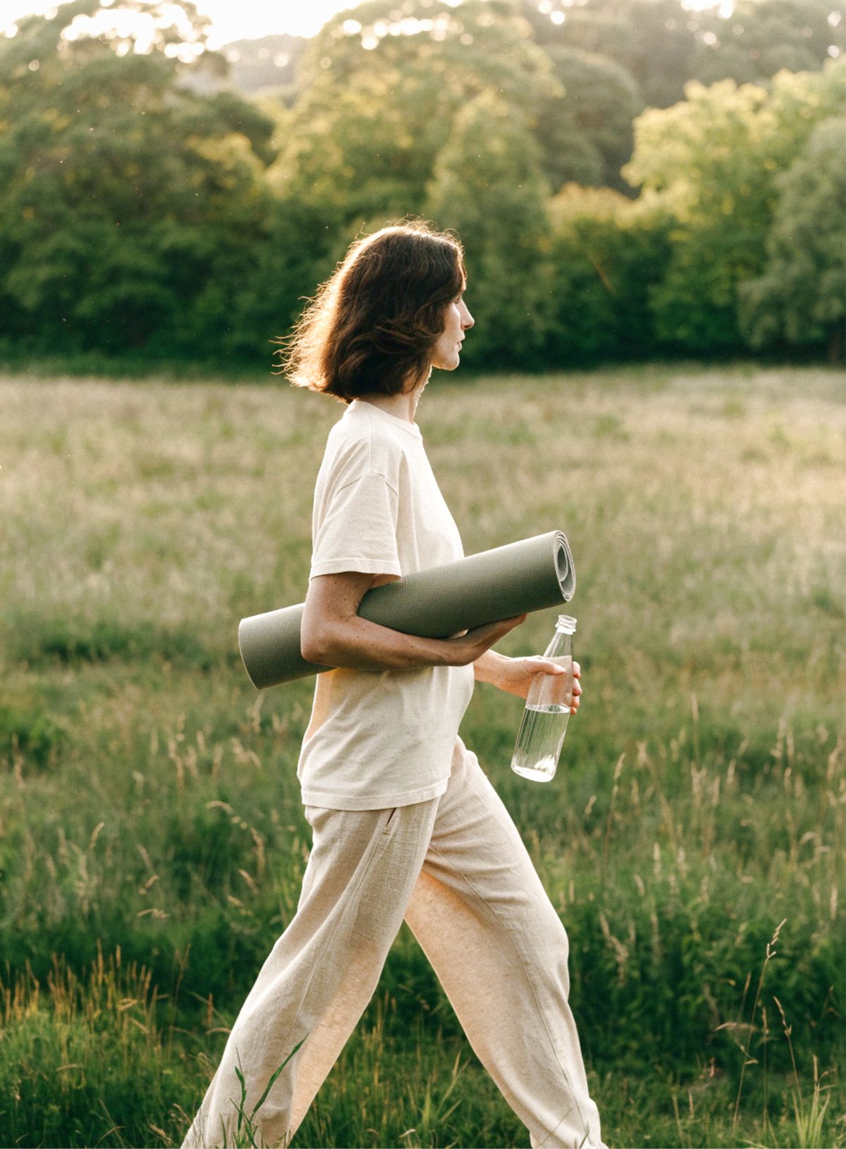 Woman walking through a field with a training mat
