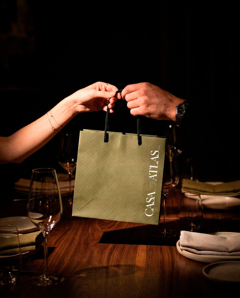 Casa Atlas bag handed across a dinner table